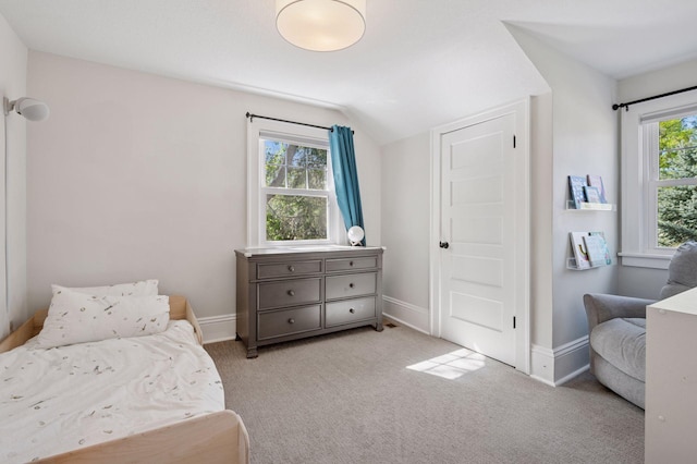 bedroom featuring lofted ceiling, light colored carpet, and baseboards