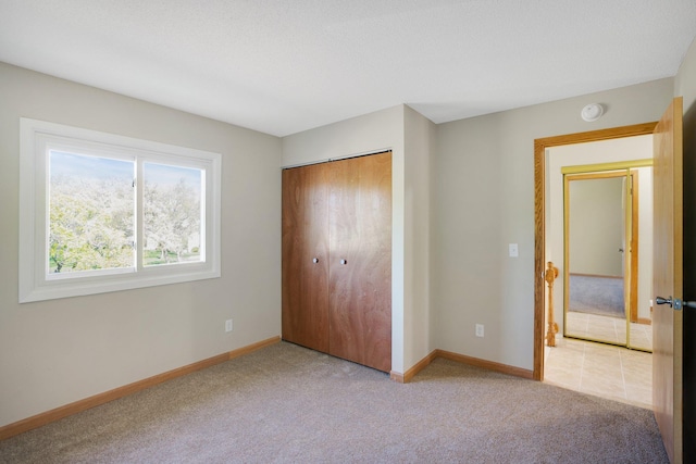 unfurnished bedroom featuring light colored carpet, a closet, and baseboards