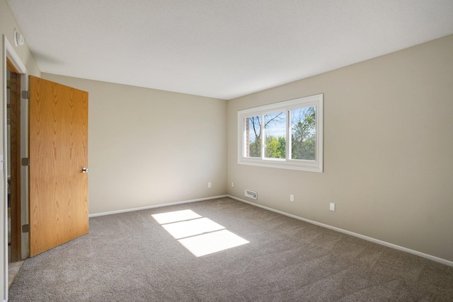 carpeted empty room featuring baseboards and a smoke detector