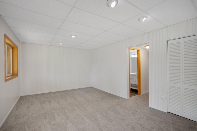 spare room featuring carpet flooring, a drop ceiling, and baseboards
