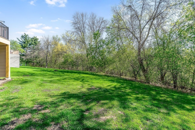 view of green lawn with a balcony