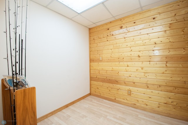 6673 230th St N, Cromwell Twp, MN 56549 - empty room with light wood-type flooring, wood walls, baseboards, and a drop ceiling