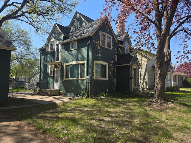 back of property with a balcony, a yard, and stucco siding