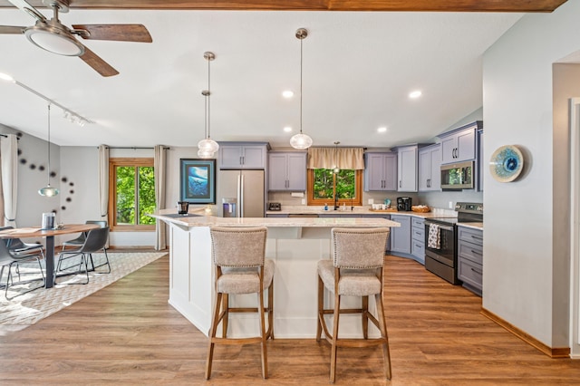 49935 Acacia Trl, Nessel Twp, MN 55080 - kitchen with stainless steel appliances, gray cabinets, a kitchen island, a breakfast bar area, and a ceiling fan