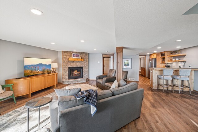 49935 Acacia Trl, Nessel Twp, MN 55080 - living area with wood finished floors, a fireplace, bar with sink, recessed lighting, and decorative columns