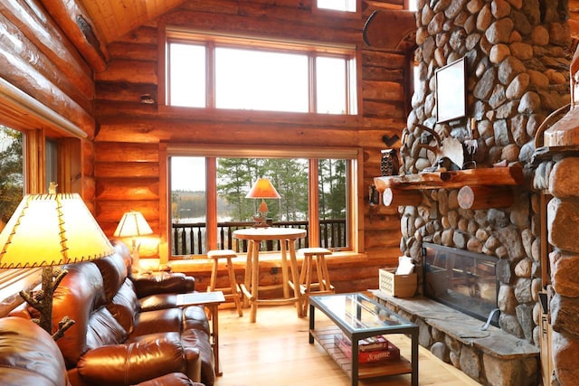 7236 Far N Rd, Buyck, MN 55771 - living area featuring rustic walls, wood finished floors, high vaulted ceiling, a stone fireplace, and plenty of natural light