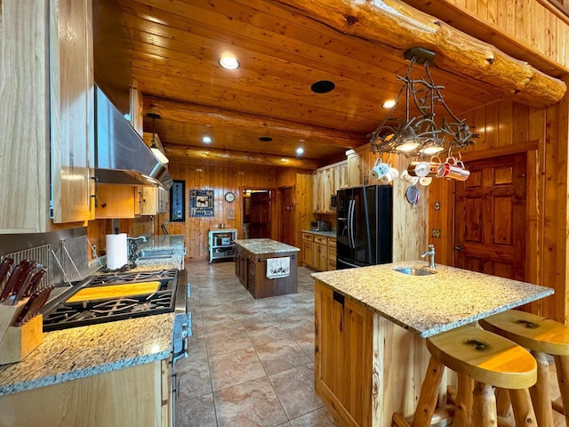 7236 Far N Rd, Buyck, MN 55771 - kitchen with black fridge, a center island, ventilation hood, gas range, and wooden walls