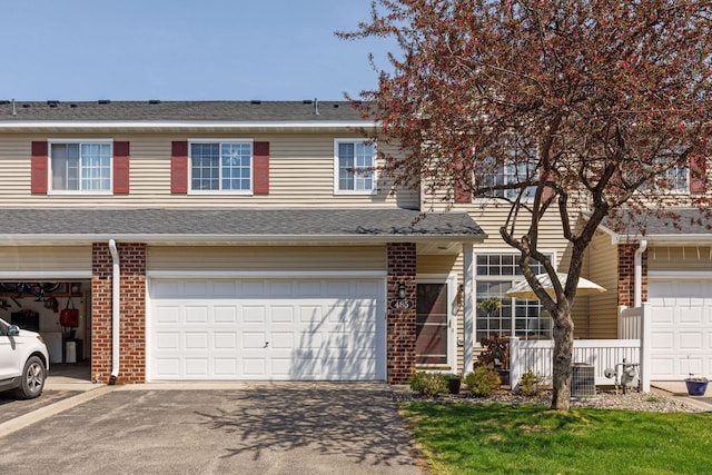multi unit property featuring brick siding, asphalt driveway, and a garage
