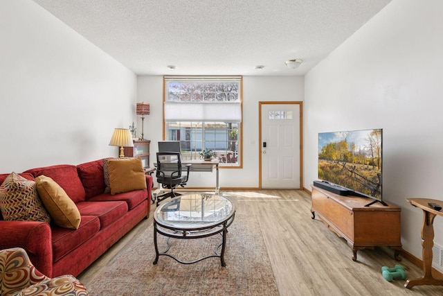 living area with wood finished floors, a textured ceiling, baseboards, and a desk