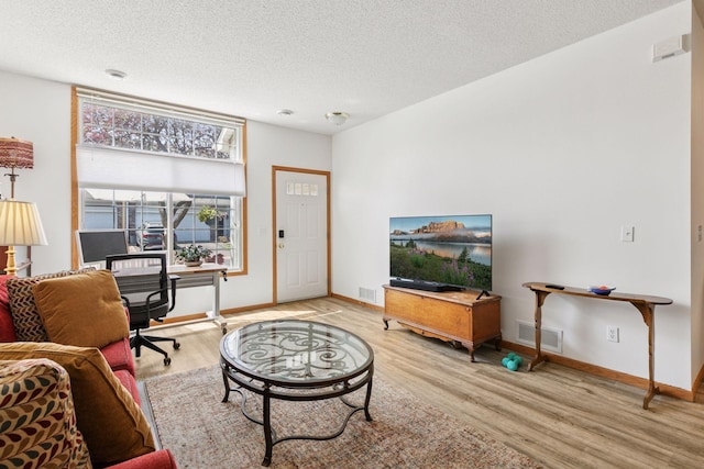 living area featuring wood finished floors, a textured ceiling, baseboards, and an office area