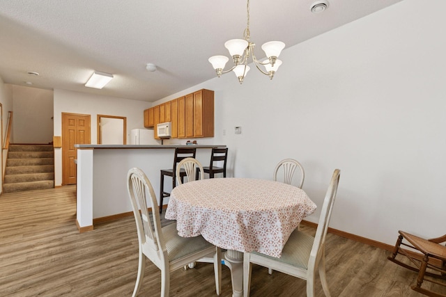 dining area with a chandelier, wood finished floors, stairs, and baseboards