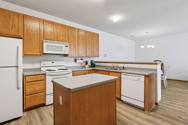 kitchen with white appliances, a sink, a peninsula, light wood-style flooring, and a chandelier