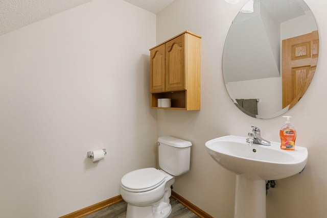 bathroom featuring a textured ceiling, toilet, wood finished floors, and baseboards