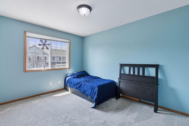 carpeted bedroom with a textured ceiling and baseboards