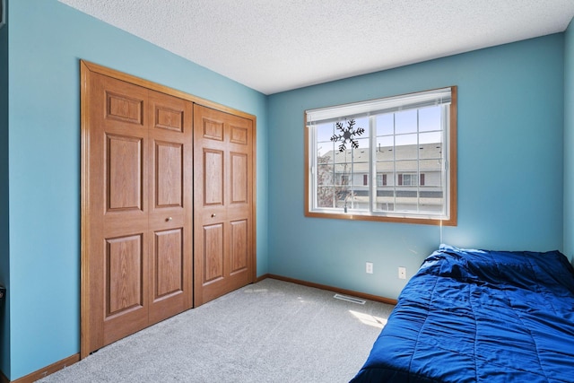 carpeted bedroom featuring baseboards, a textured ceiling, and a closet