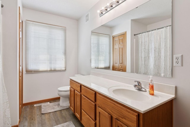 full bathroom with wood finished floors, vanity, toilet, baseboards, and curtained shower