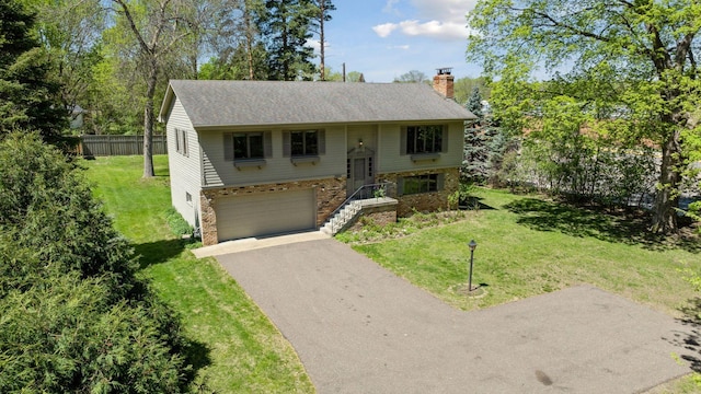 raised ranch with a chimney, driveway, a garage, a shingled roof, and brick siding