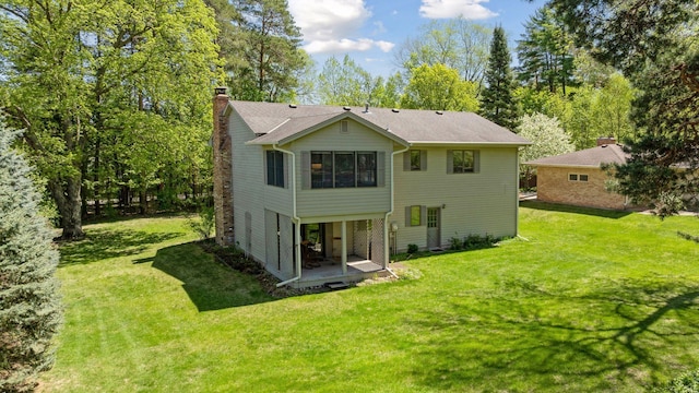 back of house with a chimney, a yard, and a patio area