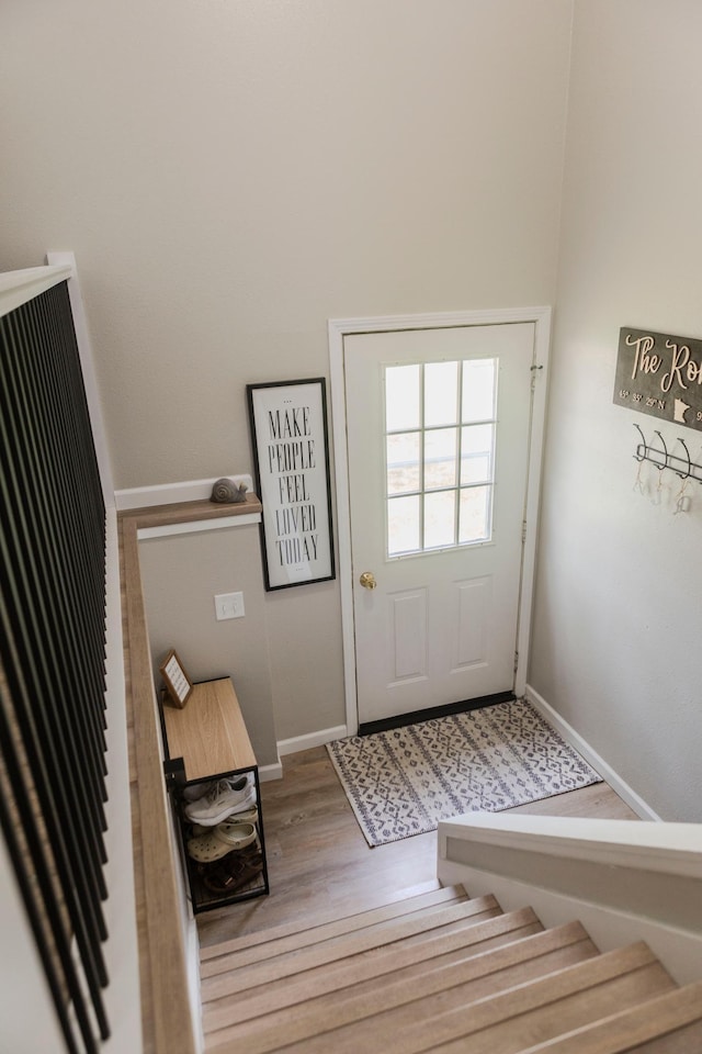 entryway featuring baseboards, wood finished floors, and stairway