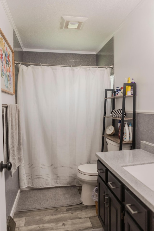 full bathroom with ornamental molding, toilet, wood finished floors, tile walls, and vanity