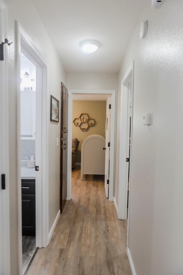 corridor featuring light wood-type flooring and baseboards