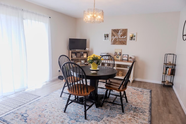 dining area with plenty of natural light, a chandelier, and wood finished floors