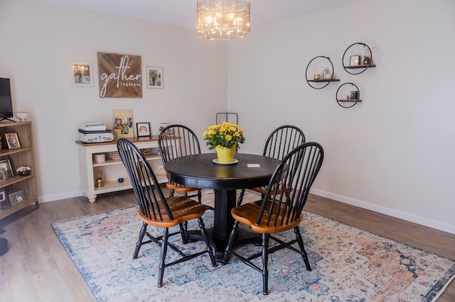dining room featuring a chandelier, baseboards, and wood finished floors