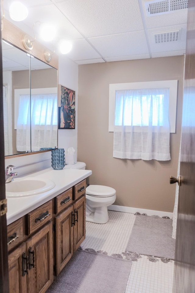 bathroom with vanity, toilet, a paneled ceiling, and tile patterned floors