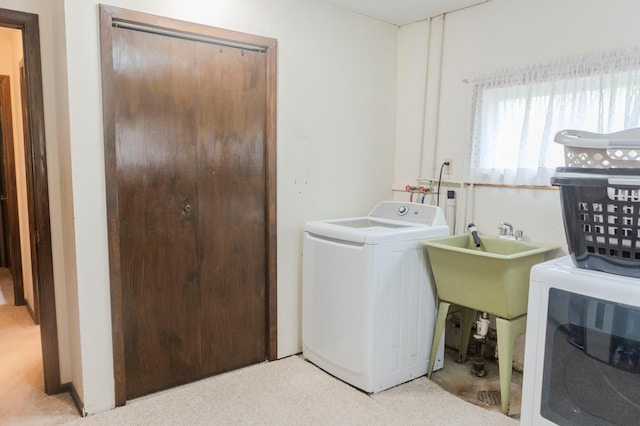 clothes washing area with light colored carpet and washer and clothes dryer