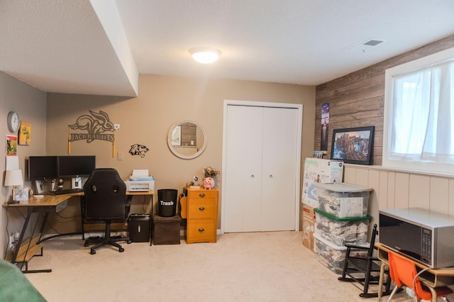 carpeted home office featuring wooden walls