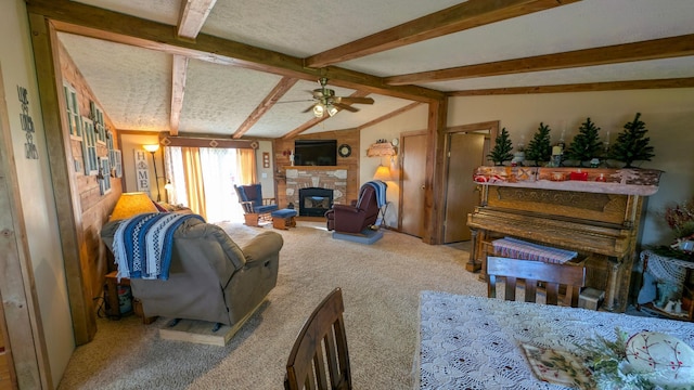 living room with a stone fireplace, carpet, and ceiling fan