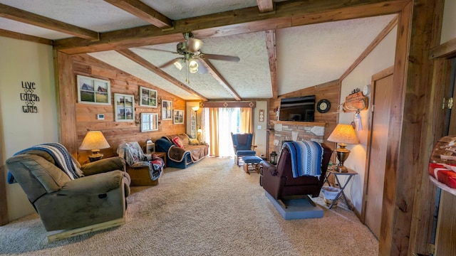 living room with wooden walls, carpet floors, ceiling fan, a fireplace with raised hearth, and a textured ceiling