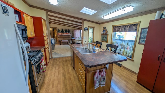 kitchen featuring appliances with stainless steel finishes, lofted ceiling, dark countertops, a sink, and light wood-type flooring