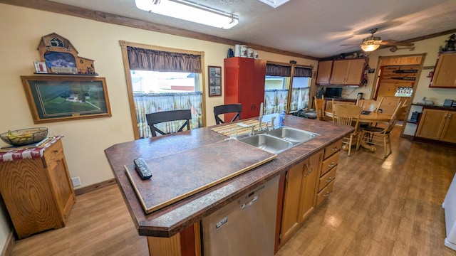 kitchen featuring dishwasher, dark countertops, a sink, healthy amount of natural light, and a textured ceiling