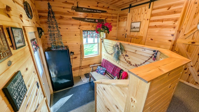 bedroom with carpet floors, vaulted ceiling, wood walls, and a barn door