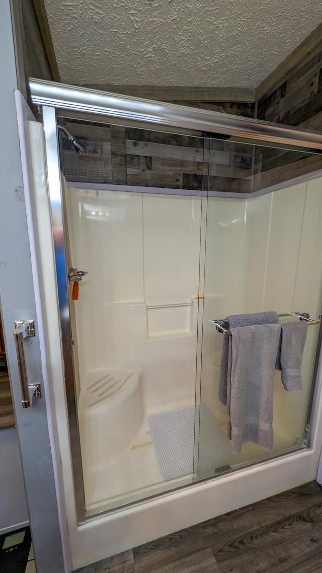 full bathroom featuring a stall shower, wood finished floors, and a textured ceiling