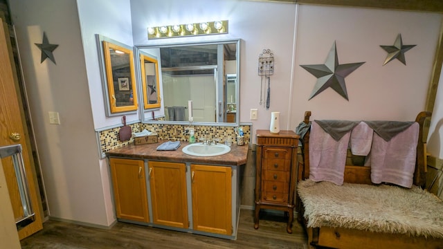 bathroom with decorative backsplash, vanity, wood finished floors, and a shower with door