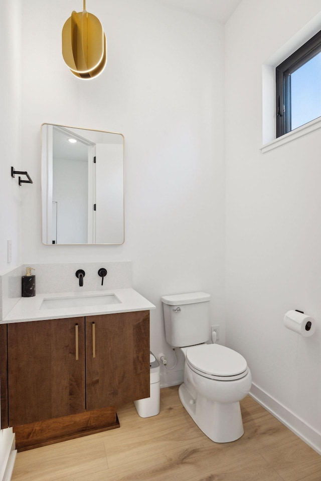 12745 Stutz Ct NE, Blaine, MN 55449 - half bathroom featuring baseboards, toilet, wood finished floors, and vanity