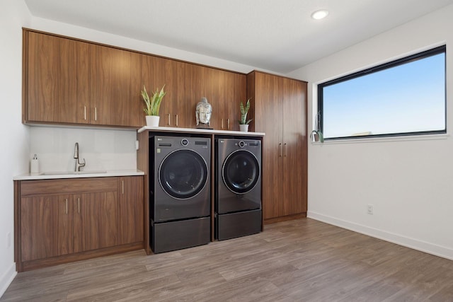 12745 Stutz Ct NE, Blaine, MN 55449 - laundry room featuring separate washer and dryer, bar with sink, light wood finished floors, baseboards, and cabinet space