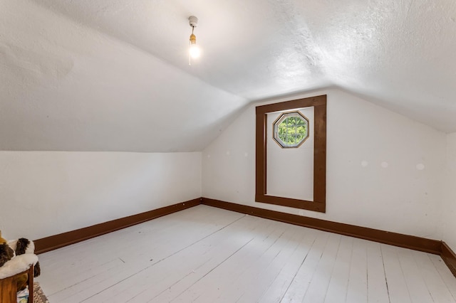 304 2nd St, Alma, WI 54610 - additional living space with light wood finished floors, vaulted ceiling, baseboards, and a textured ceiling
