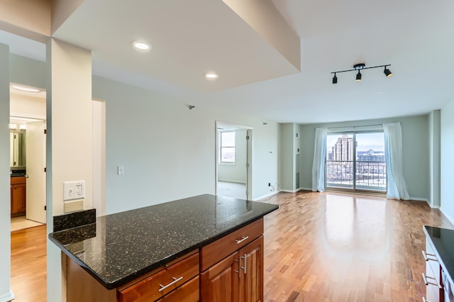kitchen featuring healthy amount of natural light, open floor plan, light wood-style floors, brown cabinets, and recessed lighting