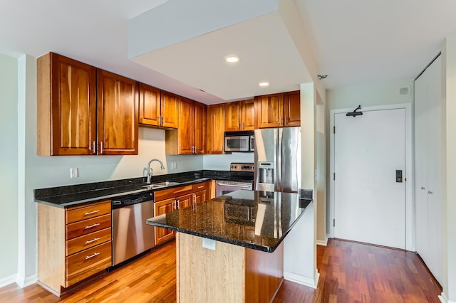 kitchen with stainless steel appliances, a sink, light wood finished floors, recessed lighting, and brown cabinetry