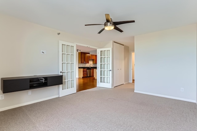 carpeted empty room featuring french doors, ceiling fan, and baseboards