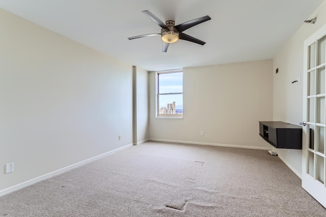 carpeted empty room with a ceiling fan and baseboards
