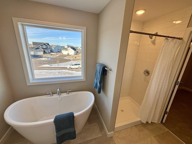 bathroom featuring a stall shower, baseboards, and a freestanding tub