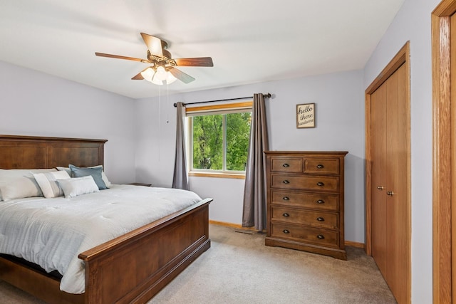 bedroom featuring light colored carpet, baseboards, and a ceiling fan