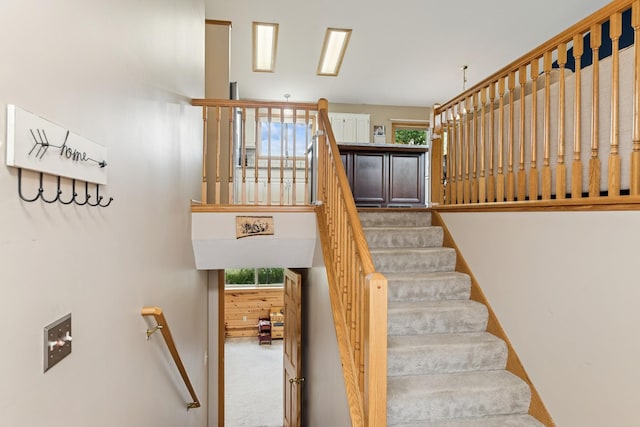 stairs with plenty of natural light and carpet