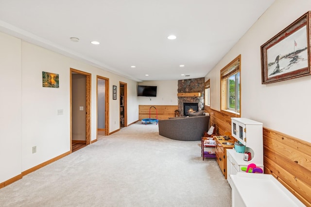 carpeted living room featuring wood walls, a fireplace, recessed lighting, and a wainscoted wall