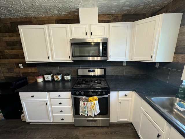 791 W Rd, Wright, MN 55798 - kitchen with appliances with stainless steel finishes, an ornate ceiling, white cabinets, dark wood-style flooring, and wood walls