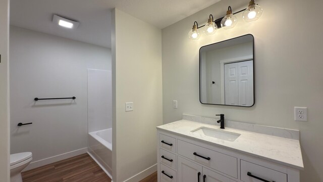 703 2nd St, Henning, MN 56551 - full bathroom featuring wood finished floors, baseboards, vanity, and toilet